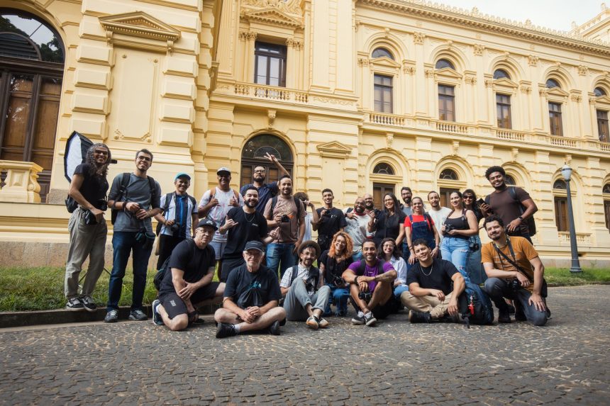 Grupo de fotógrafos reunido diante de um prédio histórico em um dia ensolarado