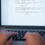 Mãos digitando um roteiro de filme em um laptop.