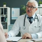 Médico conversa com paciente durante atendimento em um consultório de saúde.
