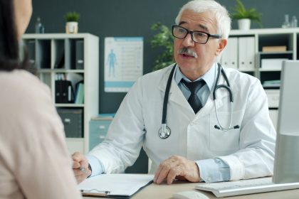 Médico conversa com paciente durante atendimento em um consultório de saúde.
