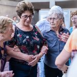 Mulheres idosas sorriem e conversam durante uma confraternização em ambiente interno.