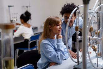 Estudantes universitários colaboram em um experimento científico em laboratório.
